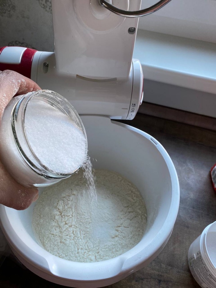 Salz wird aus einem Glas zum Mehl in die Schüssel gegeben.