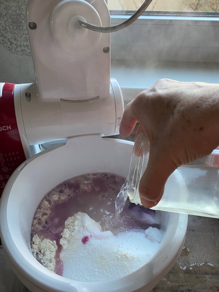 Kochendes Wasser wird in die Schüssel mit der eingefärbten Mehlmischung gegossen.