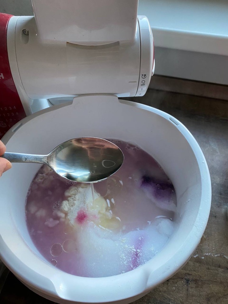Ein Löffel rührt die violett gefärbte Masse in der Schüssel um.