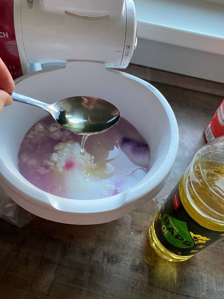 Öl wird aus einer Flasche zur angerührten Knetmasse gegeben.